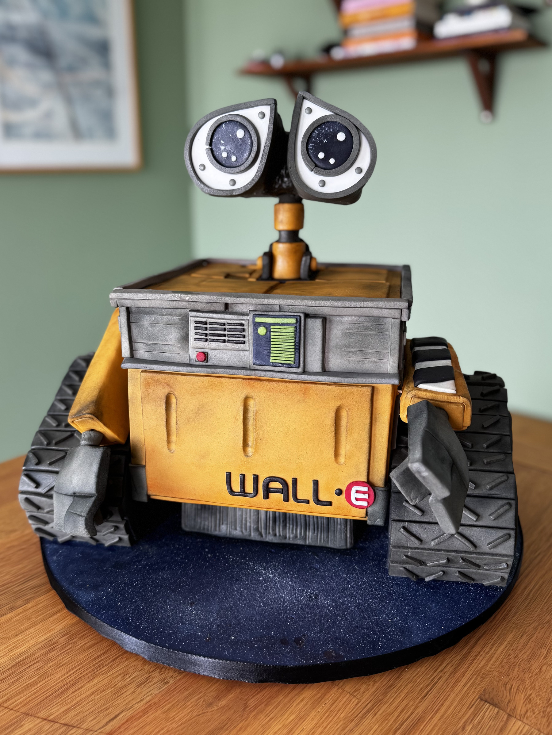 Bolo escultórico em formato do personagem Wall-E, com esteiras, braços, corpo amarelo e acabamento metalizado pintado à mão