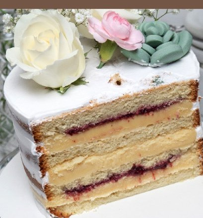 Fatia de bolo em camadas com creme claro e compota de frutas vermelhas, com rosas ao topo